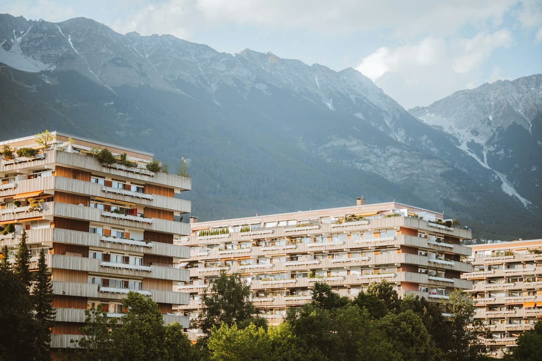 Mehrfamilienhäuser mit Balkonen vor einer Bergkette